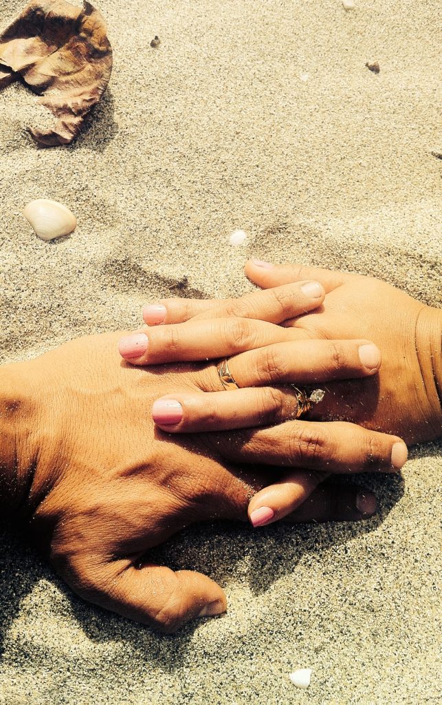 wilson-sanchez-tL9dekPndHM-unsplash | Elope to Australia Male hand and female hands with fingers entwined. Wedding rings sand.